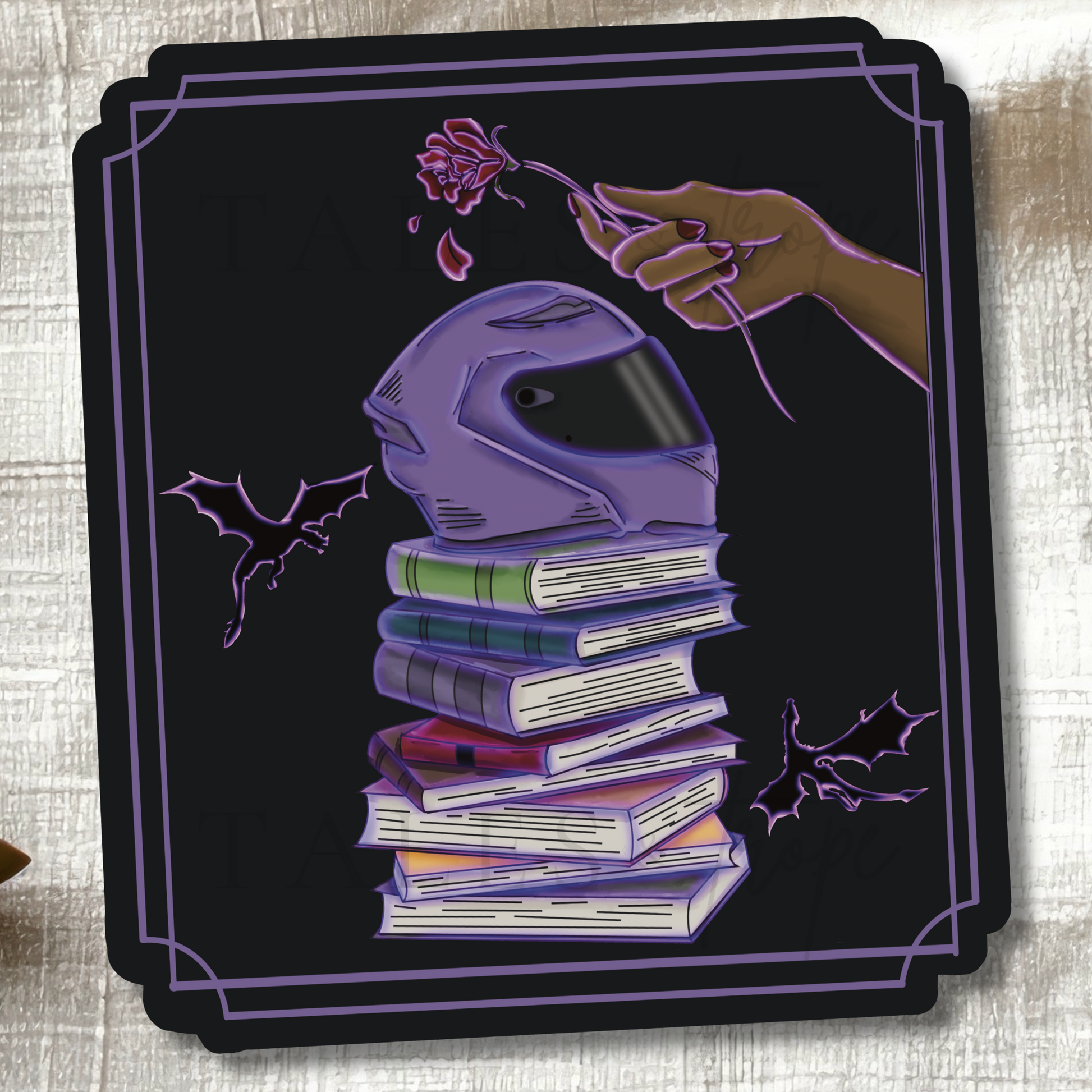 A square black sticker with a decorative purple border, featuring a stylized illustration of a purple motorcycle helmet resting on a stack of books, with a hand holding a flower above and bat silhouettes on both sides.